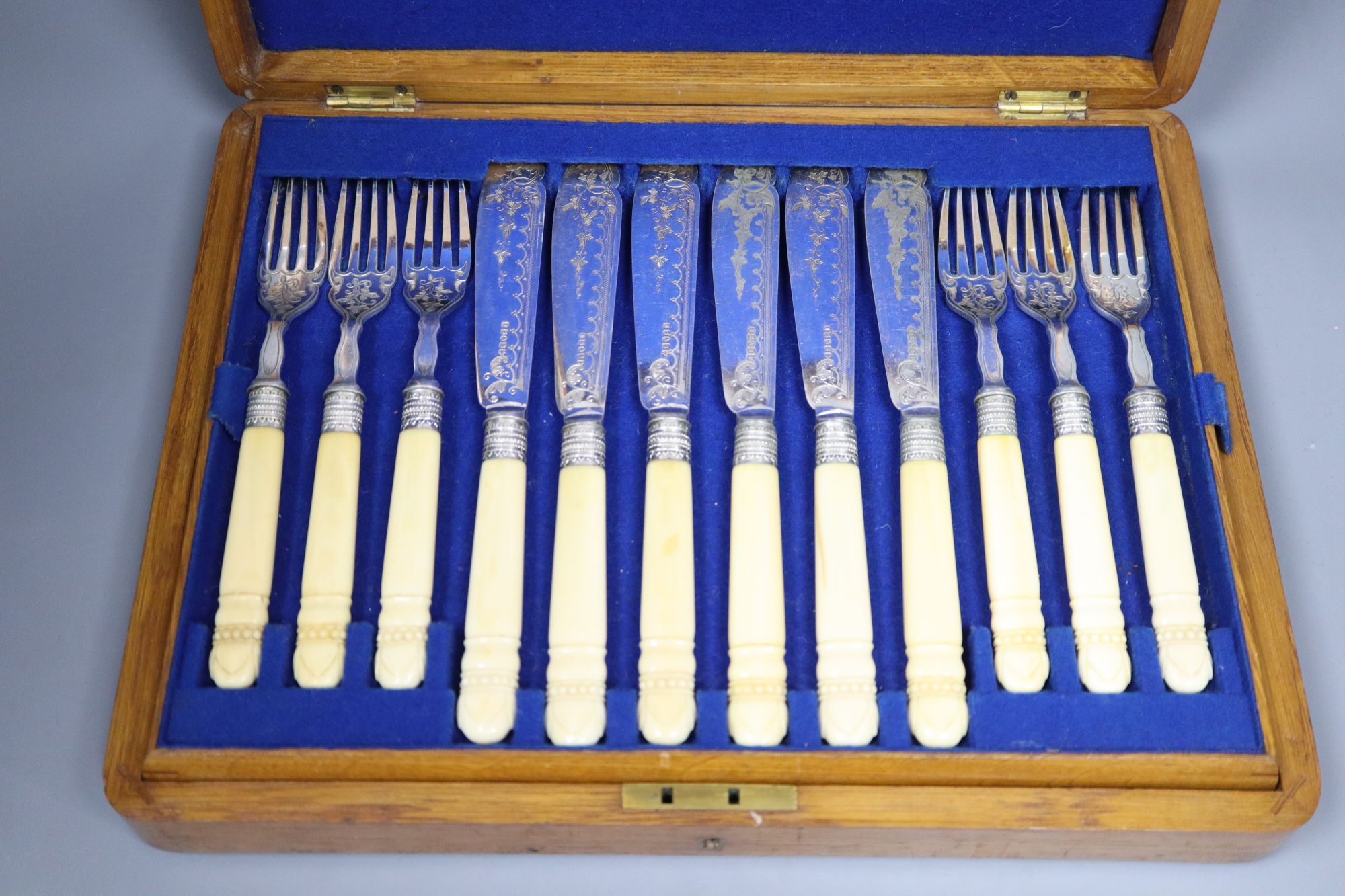 A set of twelve Victorian plated engraved carved bone handled fish knives and forks, cased